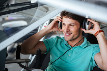 Happy man pilot sitting in cabin of small plane