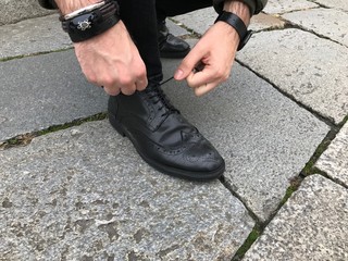 Man tying shoelaces in the street, black shoes