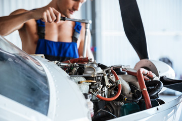 Repair man in overall fixing engine on a plane