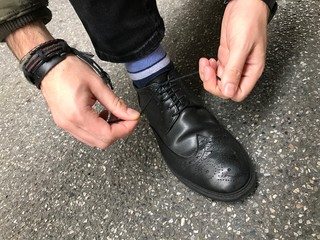 Man tying shoelaces in the street, black shoes