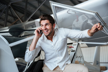 Smiling man talking on cell phone in small aircraft