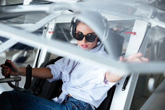 Woman Pilot In Headset Sitting In Small Plane