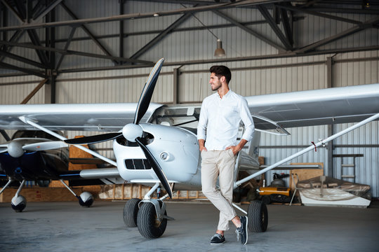 Smiling young man standing near small aircraft