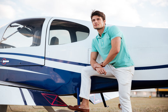 Young man pilot standing near small aircraft