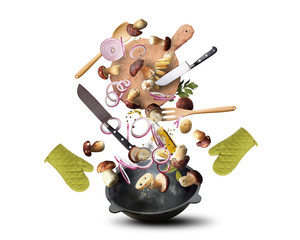Large iron skillet with falling vegetables and mushrooms