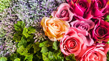 Decorative background artificial  roses and flowers on a wall