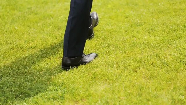 Legs of the groom in the blue pants on the green grass
