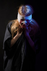 scared bloody girl with bandage on head on black background