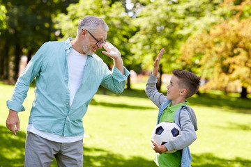 old man and boy with soccer ball making high five