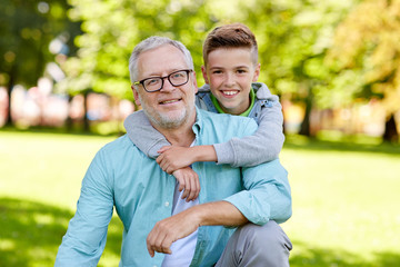 grandfather and grandson hugging at summer park