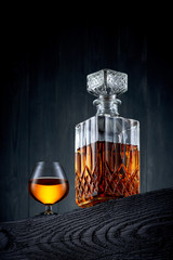 Glass and carafe of whiskey on a black wooden table - 124151215