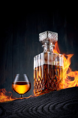 Burning carafe and glass of whiskey  on a black wooden table