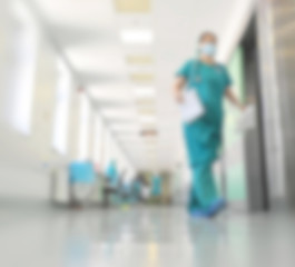 Doctors and nurses walking in hospital hallway, blurred motion.
