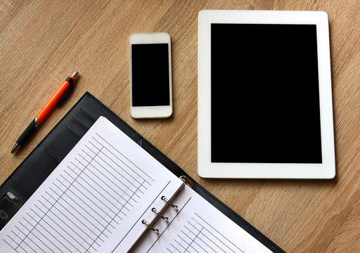 Open book,tablet computer and smartphone on working desk. Office background