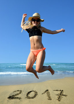 Young happiness woman jumping high by the sea while celebrating New Year 2017.
