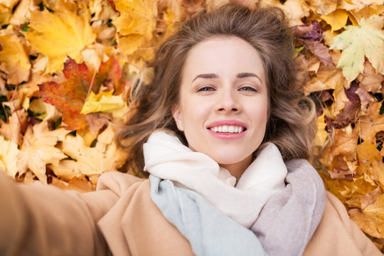 beautiful happy woman lying on autumn leaves