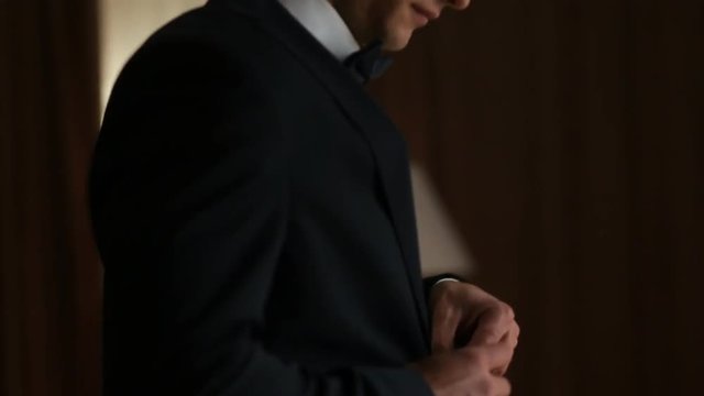 Groom buttons his wedding jacket