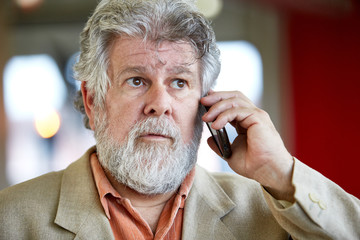 Confident male designer talking on a mobile phone in red creative office space