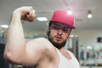 A bodybuilder guy in gym posing to show his biceps