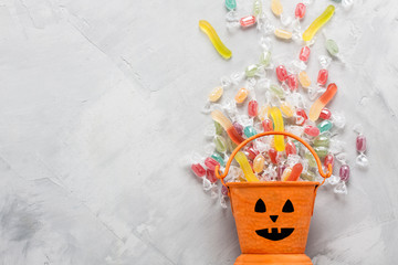 Halloween bucket with candies and jujube on gray concrete backgr