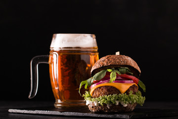 Fresh and tasty hamburger with a beer on a wooden table.