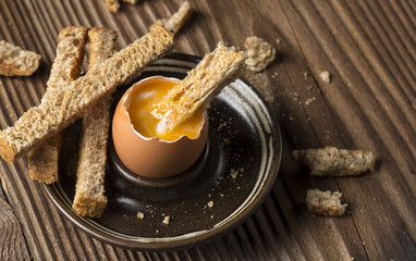 Boiled egg with crispy bread on wooden background
