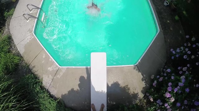 Young man does backflip off diving board, Summer pool party slow motion.