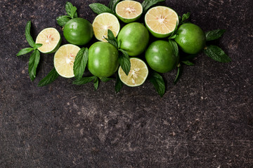 Lime background. Fresh limes with slices and mint leaves around.