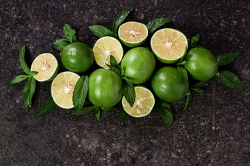 Lime background. Fresh limes with slices and mint leaves around.