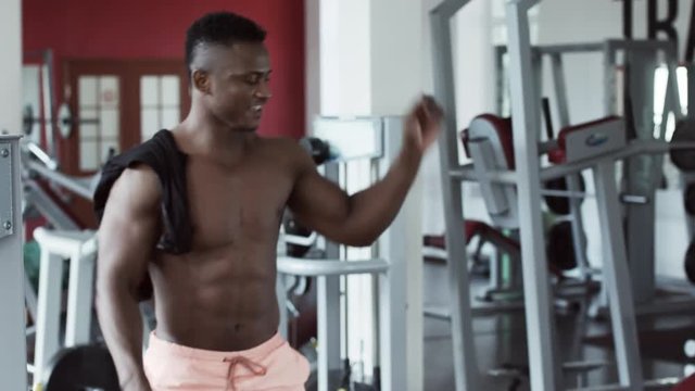 Young athletic man dancing and smiling in fitness gym, funny bodybuilder
