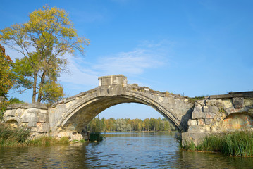 Fototapeta na wymiar The remains of the old Humpback bridge on White lake. September in Gatchina Park, Russia