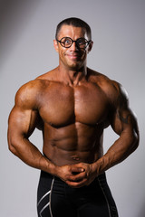 Fototapeta na wymiar Happy muscular man with a naked torso and funny glasses