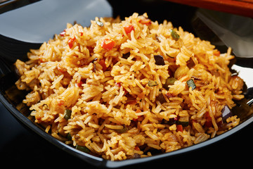 Rice with vegetables on black square dish, close up