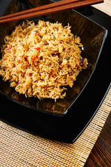 Rice with vegetables on black square dish, chopsticks