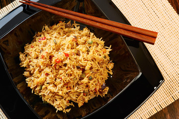 Rice with vegetables on black square dish, chopsticks