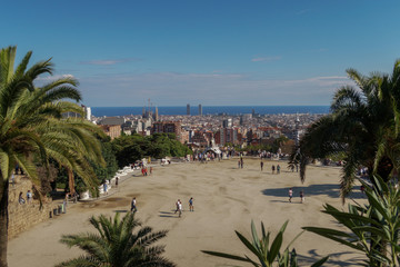 Naklejka premium Barcelona, Spain Park Guell Nature Square Placa de la Natura. Visitors on the terrace of Hypostyle Room Monumental Zone at Park Guell. Barcelona City visible in the background. 