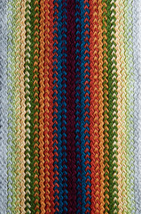 Beautiful knitted fabric scarf. Many colored threads. Knitted texture background.