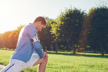 Athlete in blue shirt doing legs stretching warming before workout, lens flares