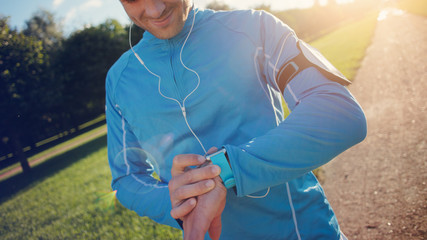 Athlete checking the program at his smart watch before running, lens flares