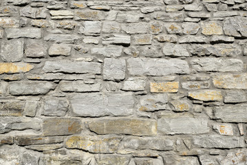 Gray pattern of old style design decorative cracked real stone wall surface with cement. Part of a stone wall, for background or texture. Antique natural stonewall background
