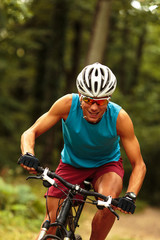 Close up image of young man riding a mountain bike on old country road.