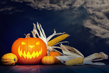 grinsender Halloween Kürbis mit Mais und Himmel