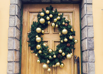 Christmas wreath with baubles and cones on a door.