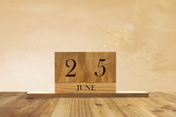 Cube shape calendar for June 25 on wooden surface with empty space for text.
