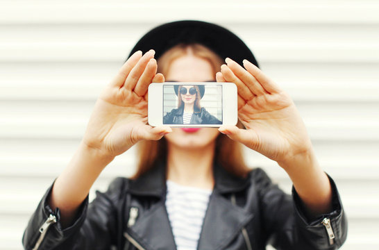 Fashion cool girl taking picture self portrait on smartphone ove