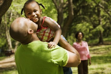 Father Kissing Daughter With Mother In Background
