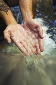 Hands Touch The Cascade Of Water At Currumbin Rock Pools In Currumbin Valley; Gold Coast, Queensland, Australia
