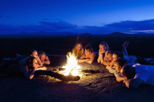 A Group Of People Laying By A Campfire; Manica, Mozambique, Africa