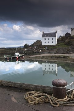 Houses Along The Water And A Boat On The Shore; St. Abb's Head, Scottish Borders, Scotland