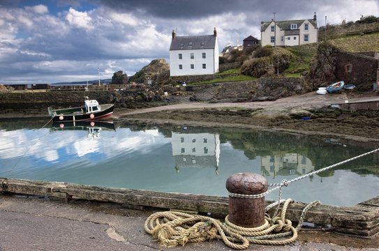 Houses And Boats Along The Water; Large Rocks In The Water Under Dark Clouds